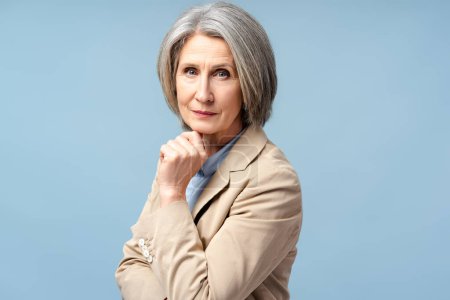 Foto de Retrato de una mujer seria de pelo gris, líder político mirando a la cámara aislada sobre fondo azul - Imagen libre de derechos