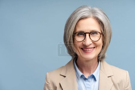 Photo for Smiling confident business woman, lawyer, financier wearing stylish glasses looking at camera isolated on blue background. Portrait of confident gray haired politician. Successful business, career - Royalty Free Image