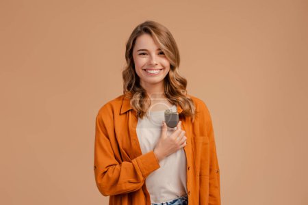 Foto de Retrato de una hermosa niña sonriente sosteniendo un marcapasos mirando a la cámara aislada sobre un fondo beige. Concepto de atención sanitaria, tratamiento - Imagen libre de derechos