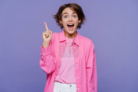 Photo for Portrait of smart excited school woman holding finger up, having idea, looking at camera with open mouth isolated on violet background. Education concept - Royalty Free Image