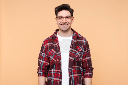 Photo for Portrait of smiling handsome man wearing stylish eyeglasses and plaid shirt looking at camera isolated on beige background. Vision concept - Royalty Free Image