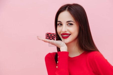 Photo for Portrait of cute beautiful smiling woman with braces holding little birthday present on palm posing at pink background. Celebration holidays concept - Royalty Free Image