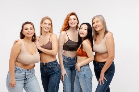 Foto de Grupo hermoso sonriente mujeres multirraciales que usan sujetadores sexy, jeans elegantes aislados sobre fondo blanco. Atractivas modelos de moda mirando a la cámara en el estudio. Diversidad, Día Internacional de la Mujer - Imagen libre de derechos