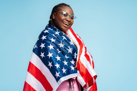 Téléchargez les photos : Portrait heureuse belle femme afro-américaine tenant drapeau américain fête de l'indépendance. 4 juillet, concept de liberté. Étudiant intelligent portant des lunettes élégantes regardant la caméra, concept éducatif - en image libre de droit