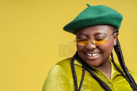 Foto de Primer plano retrato sonriente mujer afroamericana elegante con gafas de sol, boina francesa aislada en el fondo, espacio de copia. Además modelo de moda de tamaño posando en el estudio. Compras, tienda, publicidad - Imagen libre de derechos