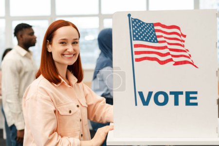 Photo for Portrait of smiling confident red haired woman vote at polling station looking at camera. Democracy, freedom, United States election day 2024 - Royalty Free Image