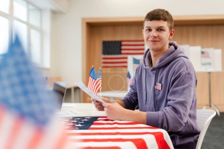 Photo for Young smiling man, voter holding paper ballot waiting registration at polling station. Election concept - Royalty Free Image