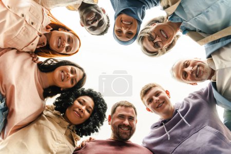 Foto de Retrato grupal de gente de negocios multirracial sonriente mirando a la cámara abrazándose de pie en círculo. Trabajadores confiados, colegas en la oficina moderna. Reunión. Negocios exitosos, carrera, equipo de startups - Imagen libre de derechos