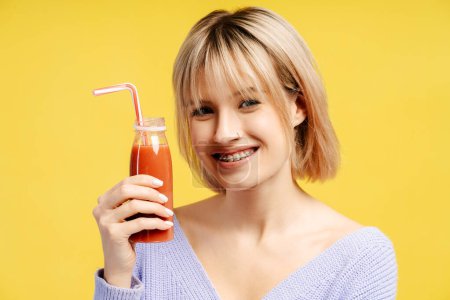 Photo for Happy woman holding juice red smoothie as detox diet, looking at camera isolated on yellow background. Proper nutrition healthy fast food. Healthy choice concept - Royalty Free Image