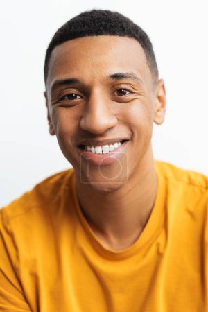 Téléchargez les photos : Portrait d'un homme afro-américain attrayant et souriant regardant une caméra debout isolée sur fond blanc, gros plan. Publicité, concept dentaire - en image libre de droit