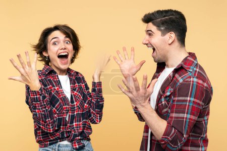 Photo for Portrait photo of an overjoyed people, excited woman and a surprised man, gesticulating as winners, celebrating an unbelievable victory, posing on a yellow background and looking at the camera - Royalty Free Image
