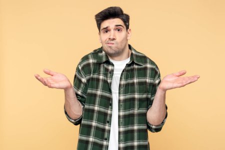 Photo for Portrait photo of a disappointed, upset man making a hand gesture, showing doubt through his facial expression, posing against an isolated yellow background, and looking at the camera - Royalty Free Image
