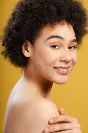 Foto de Mujer latina atractiva sonriente con peinado elegante, pelo rizado mirando a la cámara. Modelo de moda posando sexy aislado sobre fondo amarillo. Concepto de belleza, publicidad - Imagen libre de derechos