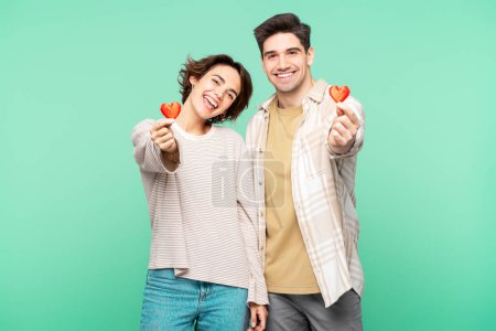 Photo for Happy romantic couple holding red paper hearts celebration Valentines day isolated over turquoise background. Dating, love concept - Royalty Free Image
