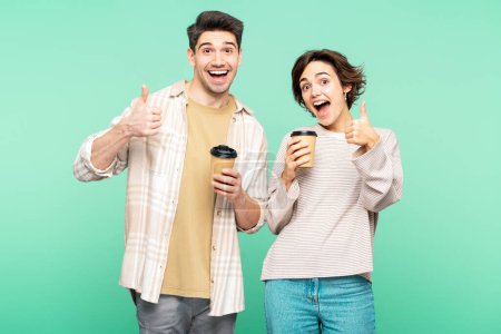 Photo for Portrait of smiling beautiful couple wearing casual clothes holding cups of coffee looking at camera drinking isolated on turquoise background. Coffee break concept - Royalty Free Image