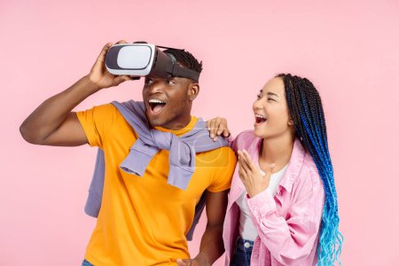 Téléchargez les photos : Des amis afro-américains étonnants portant des lunettes VR jouant au jeu vidéo, isolés sur fond rose. Concept innovant, simulation 3D - en image libre de droit