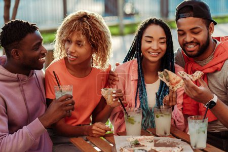Foto de Grupo de amigos afroamericanos positivos diversos, reunión en la fiesta de cumpleaños, sentado en la cafetería, beber limonada al aire libre. Concepto de celebración - Imagen libre de derechos