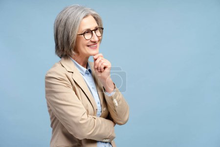 Foto de Mujer de negocios sonriente con anteojos mirando hacia otro lado, pensando aislado en el fondo azul. Retrato de un político de pelo gris seguro. Negocios exitosos, carrera - Imagen libre de derechos