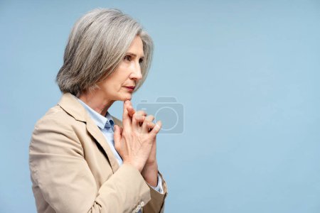Senior sad businesswoman looking away and thinking problems isolated on blue background. Stress, depression concept