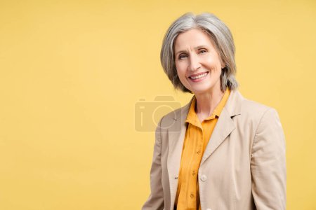 Smiling confident business woman, lawyer, financier looking at camera isolated on yellow background. Portrait of confident gray haired politician. Successful business, career
