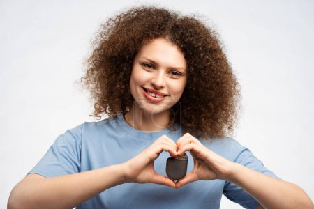 Photo for Smiling beautiful young woman wearing blue t shirt holding pacemaker looking at camera isolated on white background, closeup. Concept of health care, treatment of heart - Royalty Free Image