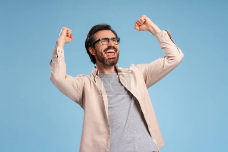 Photo for Handsome young man wearing glasses over isolated blue background very happy and excited, doing winner gesture with arms raised. Celebration concept - Royalty Free Image