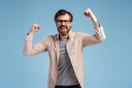 Photo for Young handsome man in glasses shouting triumphantly, laughing and feeling happy and excited while celebrating success. Lifestyle, people concept - Royalty Free Image