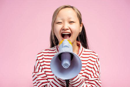 Photo for Cute Asian girl looking at camera posing making announcement with megaphone in hands, isolated on pink background. Shopping, sale concept. Advertisement - Royalty Free Image