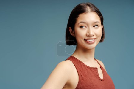 Téléchargez les photos : Portrait d'une jeune femme souriante heureuse regardant la caméra, posant sur un fond bleu isolé. Sport, endurance et concept de force - en image libre de droit