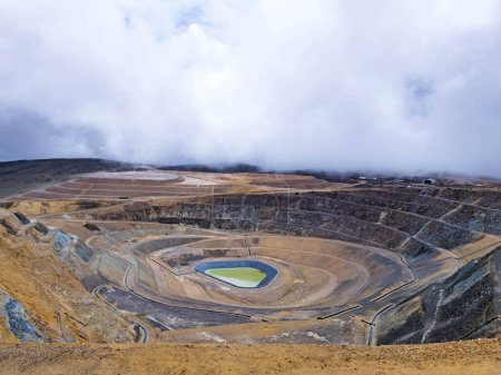 Panoramic view of an open pit mine with a lagoon in the background