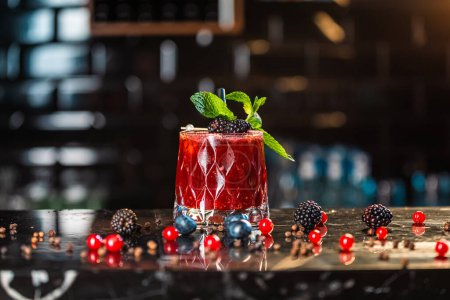 Téléchargez les photos : Un cocktail rouge avec des baies sur une table - en image libre de droit