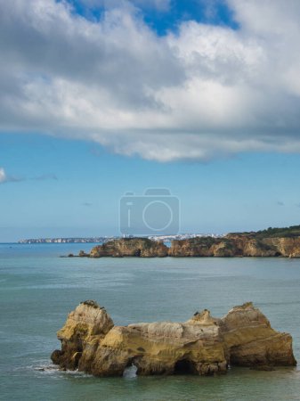 Foto de Portimo Paisaje costero, Algarve, Portugal, en un día de cielo azul. Enorme océano con olas, rocas en medio del mar y acantilados. - Imagen libre de derechos