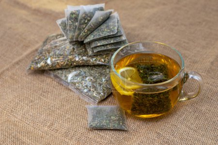 Téléchargez les photos : Herbal tea with homeopathic products, nature herbs in sachets and bags on burlap background in rustic style - en image libre de droit