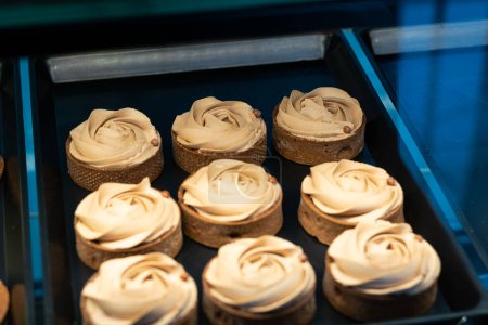 Photo for Many mini tarts cakes with chocolate cream in the display case in the pastry shop - Royalty Free Image