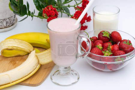 Téléchargez les photos : Smoothies à la banane et aux fraises, fruits sur la table, dans l'assiette, préparation à la maison - en image libre de droit