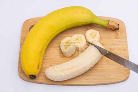 Téléchargez les photos : Banane coupée au couteau sur fond en bois dans la cuisine - en image libre de droit