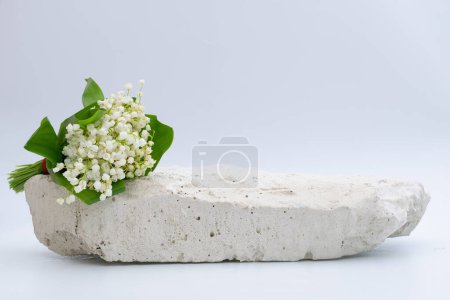 Foto de Fondo natural del producto, plataforma de piedra blanca por encima de la cual hay un ramo de flores de lirio de agua blanca, sobre un fondo blanco - Imagen libre de derechos