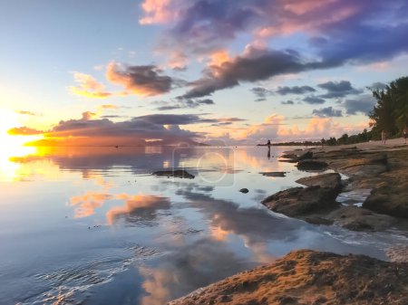 Photo for Bright tropial sunset reflected in ocean water. Colorful clouds in sky and rocky seashore. Amazing natural summer scenery. Wonderful Nature landscape during sunset. Travel, tourism, relax. - Royalty Free Image