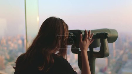 Téléchargez les photos : Femme profiter Bangkok paysage urbain sur Baiyoke Tower Sky point de vue. Fille à la recherche dans le télescope jumelles sur la plate-forme d'observation pour les touristes. Panorama de la ville au coucher du soleil. Voyage, tourisme, visite Thaïlande - en image libre de droit