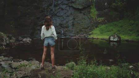 Woman standing on rock enjoy tropical rainforest landscape. Exotic jungle scene forest. Travel, tourism, trekking, hiking, relax, active lifestyle. Dramatic toning. Panoramic drone shot, back view