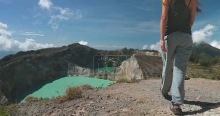 Téléchargez les photos : Une femme se tient au sommet d'une montagne, regardant à travers une vue imprenable sur un lac niché dans la vallée ci-dessous. Le paysage comprend un lac de cratère volcanique aux Philippines. - en image libre de droit