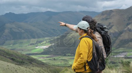 Téléchargez les photos : Jeune couple latino-américain avec des sacs à dos explorant en pleine nature sur une montagne lors d'une journée ensoleillée - en image libre de droit