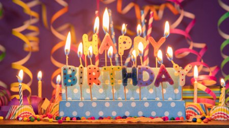 Téléchargez les photos : Bougies lumineuses de différentes couleurs en forme de lettres formant la phrase HAPPY BIRTHDAY, sur un fond violet flou avec banderole - en image libre de droit