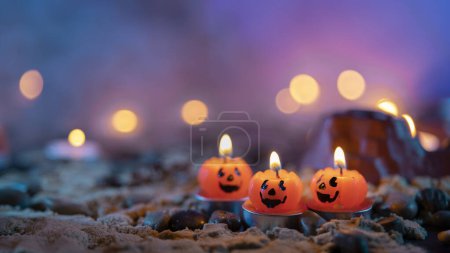 Téléchargez les photos : Fond Halloween, 3 bougies en forme de citrouille au premier plan sur un fond flou avec des lumières jaunes - en image libre de droit