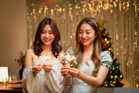 Photo for Young beautiful people holding sparkler lights firework with enjoying in night while dinner to celebrating in new year party festive at home. - Royalty Free Image
