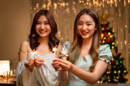 Photo for Young beautiful people holding sparkler lights firework with enjoying in night while dinner to celebrating in new year party festive at home. - Royalty Free Image