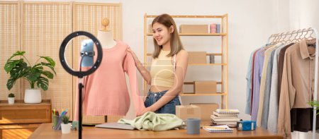 Photo for Woman designer entrepreneur showing sweater of new collection in mannequin and review product with detail while selling clothes product on live online social media streaming. - Royalty Free Image