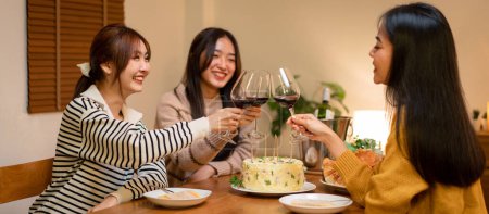 Photo for Young smiling woman drinking and clinking glass of wine to toasting with happiness while celebrating in new year party at home. - Royalty Free Image