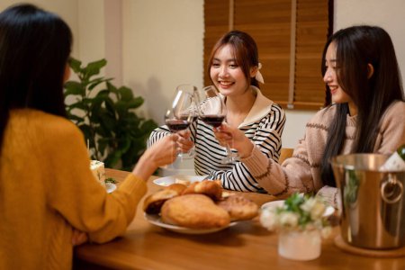 Foto de Joven mujer sonriente bebiendo y tintineo copa de vino para brindar con felicidad mientras se celebra en la fiesta de año nuevo en casa. - Imagen libre de derechos