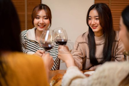 Foto de Joven mujer sonriente bebiendo y tintineo copa de vino para brindar con felicidad mientras se celebra en la fiesta de año nuevo en casa. - Imagen libre de derechos